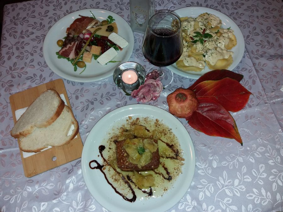tri servirana jela na stolu uz čašu crnog vina na izletištu Casa Rustica