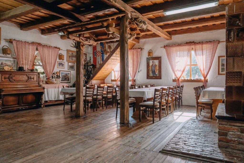rustikalan izgled sale s drvenim stropom i gredama, drvenim stolovima i stolcima i crveno-bijelim zavjesama na seoskom turizmu Bistrički
